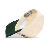 The Fort Collins Hometown Hat by No Rivals is displayed upside down, showing the inside NO RIVALS label. It features a cream crown, dark green brim, and a small side logo for a structured fit.