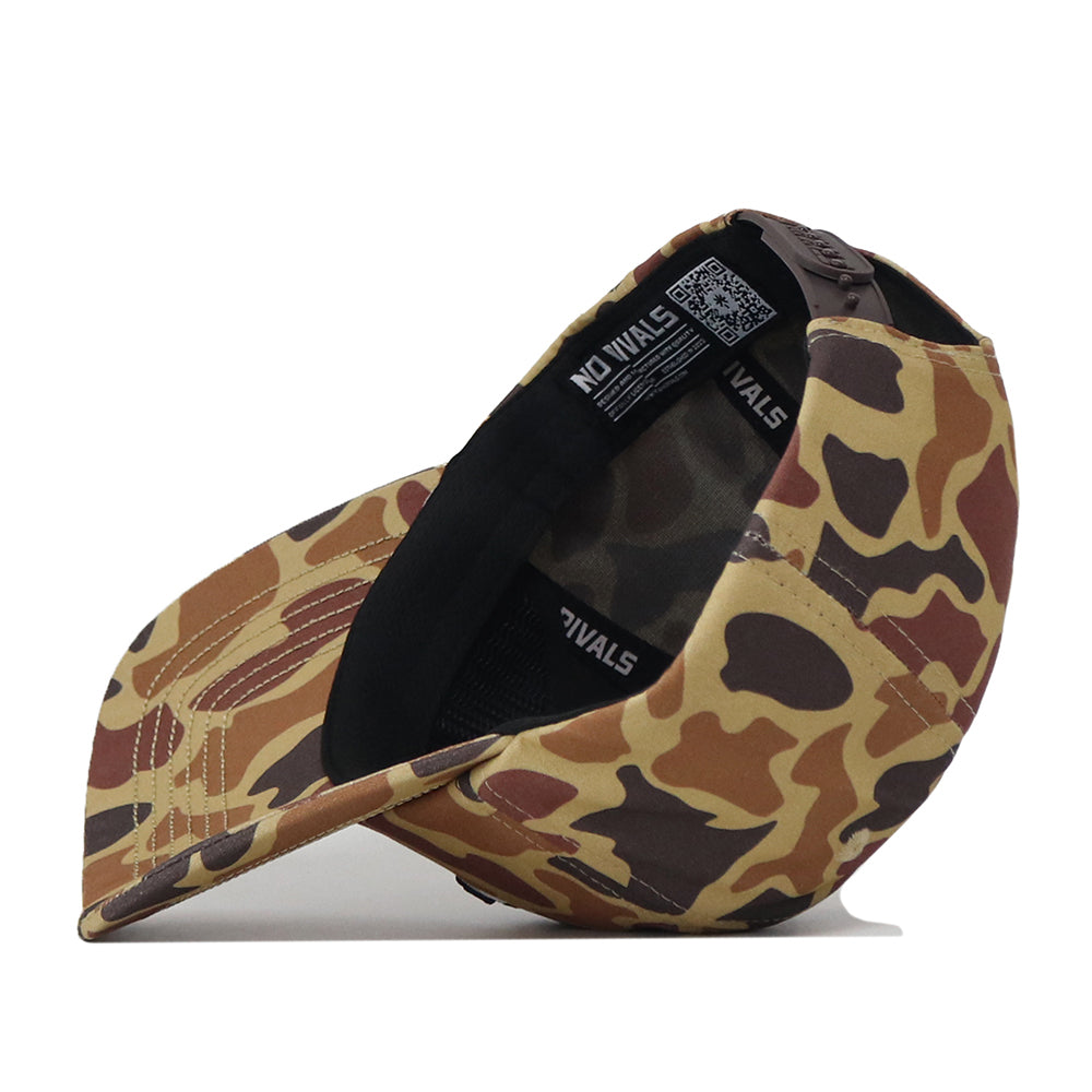The South Dakota State Huntsman Hat by No Rivals is a camo-patterned baseball cap, displayed flipped to reveal its interior, which features a black lining with NO RIVALS text and a QR code on the tag. Made from high-quality cotton, this rugged hat showcases brown, tan, and green camouflage colors. It also includes a convenient snapback adjustment for a customizable fit.