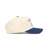 The No Rivals Florida Gators 250th Americana Hat is a cream snapback with a navy brim, shown from the side, featuring an embroidered logo and a small American flag on the front right panel.