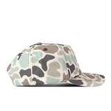 A side view of the No Rivals WVU Mountaineers Huntsman Hat, a snapback hat featuring a green, brown, beige, and black camouflage pattern made from high-quality cotton, displayed on a white background.