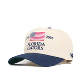 The Florida Gators 250th Americana Hat by No Rivals is a beige and navy snapback with an embroidered American flag, 1776, 2026, Florida Gators on the front, and features an official logo plus "NF" on the brim.