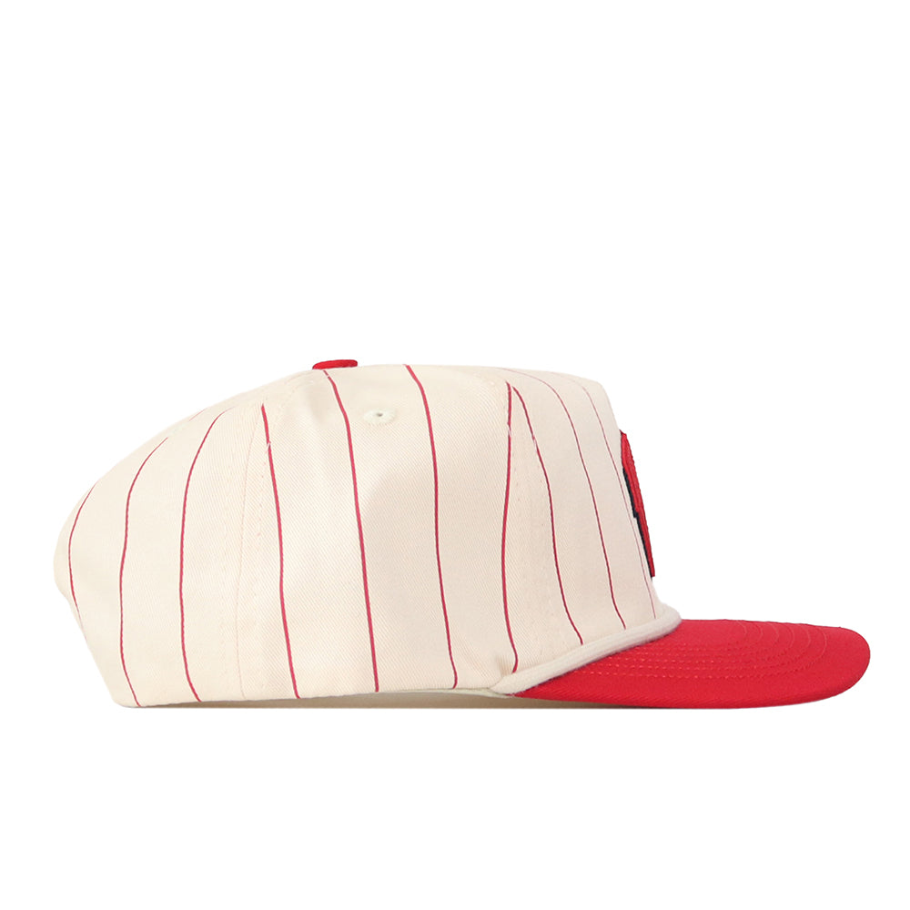 The No Rivals Wisconsin Pinstripe Hat is a cream-colored baseball cap with thin red vertical stripes and a solid red brim, featuring a snap back adjustment for a customizable fit. It is shown from the side on a white background.