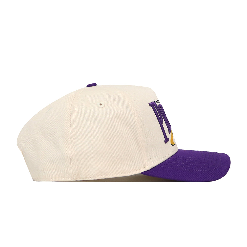The No Rivals ECU Pirates Stride Hat, featuring a beige snapback design with a purple brim and partially purple embroidered side logos, is displayed in a side view against a white background.
