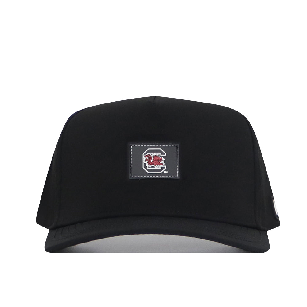 The No Rivals South Carolina Gamecocks Trainer Hat is a black snapback cap featuring a rectangular patch with a red and white graphic design on the front. Made from high-quality cotton, this structured hat is shown against a plain white background.