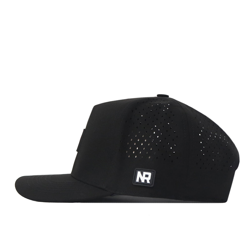 The South Carolina Gamecocks Trainer Hat by No Rivals is a black flat-brimmed cap shown from the side, featuring a structured fit with perforations for ventilation and a small rectangular NR logo patch on the side panel. Crafted from high-quality cotton, this snapback hat combines comfort and style for everyday wear.