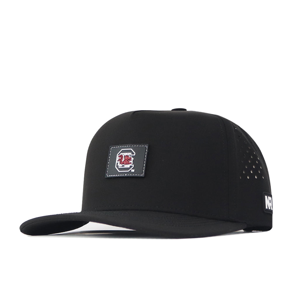 Introducing the South Carolina Gamecocks Trainer Hat by No Rivals—a stylish black snapback cap featuring a prominent red and white Gamecock logo patch on the front, small ventilation holes on the sides, and NR branding on the brim. Crafted from quality cotton for lasting comfort and durability, this structured snapback offers both fashion and function for any Gamecocks fan.