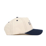 The No Rivals University of Illinois Vintage Hat is a beige snapback with a dark blue brim, viewed from the side. It features high-quality cotton, dark stitching, ventilation eyelets, and partial front text.