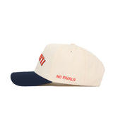 The Upside Down Illinois Hat by No Rivals is a cream cotton baseball cap with a navy blue brim and “NO RIVALS” embroidered in red on the side.