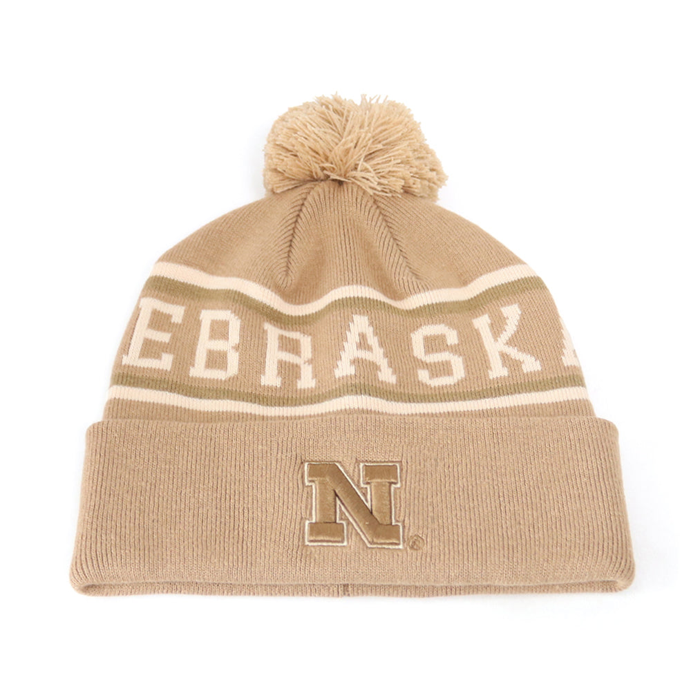Show your team spirit with the Nebraska Cornhuskers Desert Beanie by No Rivals, a tan knit beanie with a pom-pom on top. This high-quality cotton hat features “NEBRASKA” and a large, embroidered N logo on the front cuff, and is officially licensed for authentic fan pride.