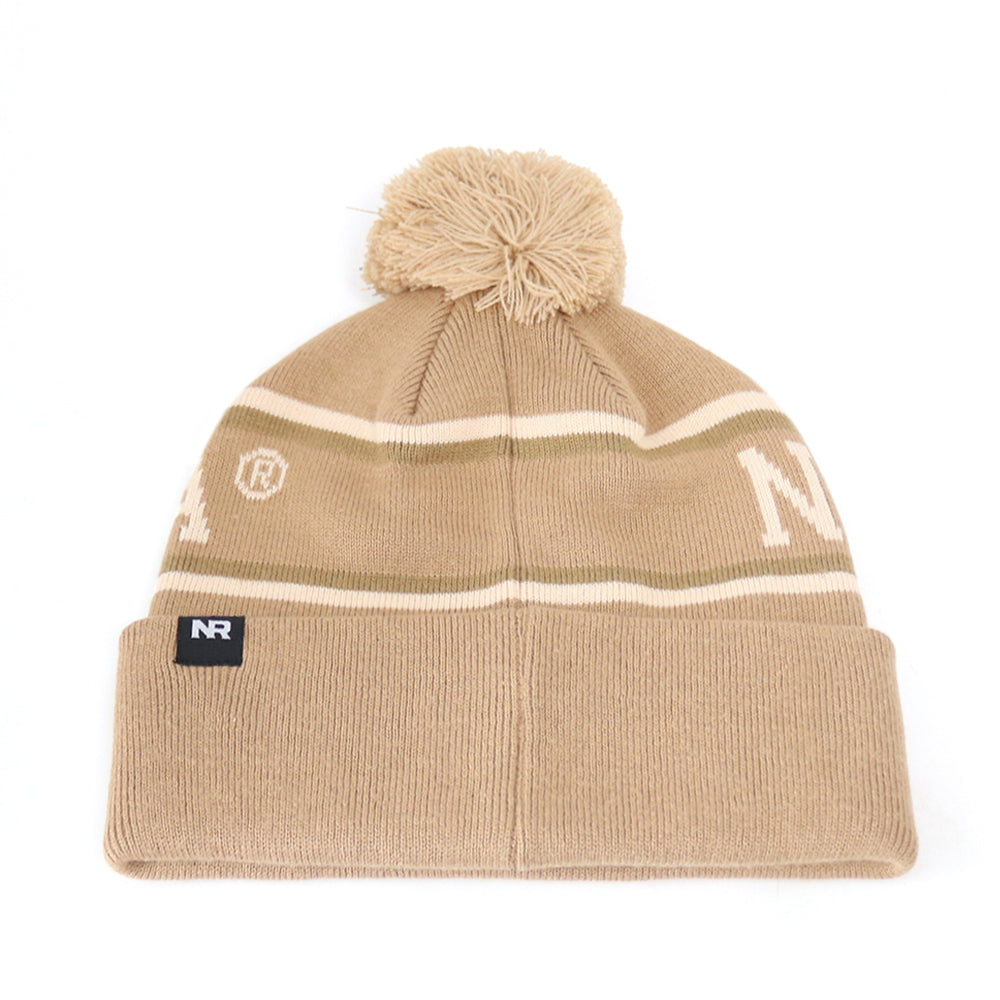 The Nebraska Cornhuskers Desert Beanie by No Rivals features a tan knit design with white and olive green stripes, a pom-pom on top, and an officially licensed NR embroidered logo on the front cuff. Made from high-quality cotton for lasting comfort and durability.