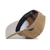 The Nevada Rustic Hat by No Rivals is a tan cotton canvas hat with a black NO RIVALS interior band, a light gray underside of the brim, and a small dark blue embroidered bird on the side.