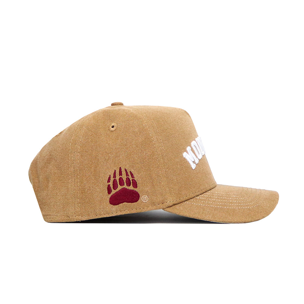 The No Rivals Montana Rustic Hat is a tan cotton canvas cap with a structured fit, curved brim, raised white lettering on the front, and a red bear paw print logo on the side.