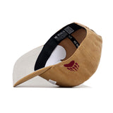 The Montana Rustic Hat by No Rivals is a tan and beige cotton canvas snapback, shown on its side with a black inner band featuring "NO RIVALS" text and a red paw print logo on the outer side for a structured fit.