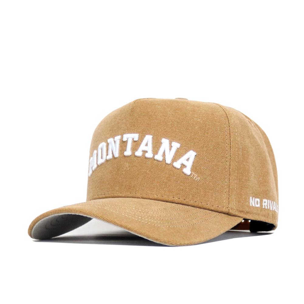 The Montana Rustic Hat by No Rivals is a tan cotton canvas snapback with "MONTANA" embroidered in white on the front and "NO RIVALS" stitched on the side, offering classic style and modern comfort.