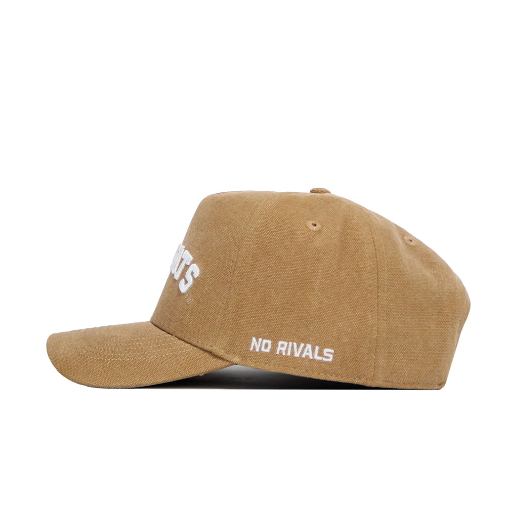 The Kansas State Rustic Hat by No Rivals is a tan cotton canvas baseball cap, seen from the side, with white "NO RIVALS" embroidery on the side panel.