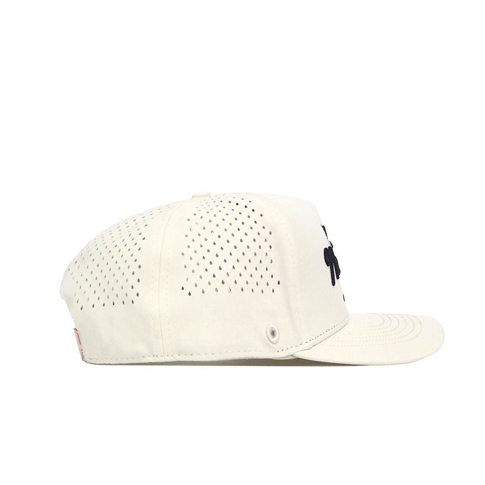 Side view of the No Rivals Golf Hat - Tan by No Rivals, an off-white snapback cap with black vents, flat brim, and a small black embroidered logo on the front. Displayed on a white background—ideal for your gameday fit.