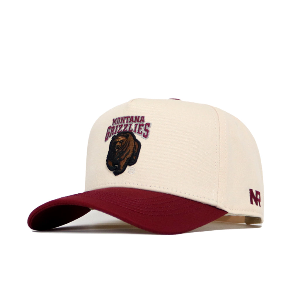 The Montana Logo Patch Hat by No Rivals features a cream snapback, maroon brim, high-quality cotton blend, embroidered Montana Grizzlies logo with bear head patch on the front, and "NR" stitched on the side.