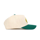 The No Rivals NDSU Logo Patch Hat is a cream snapback with a green brim, shown from the side on a white background. Made from high-quality cotton, it features an embroidered NDSU logo patch on the front panel.