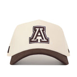 The Arizona Espresso Hat by No Rivals is a structured fit baseball cap in high-quality beige cotton, featuring a brown brim and a large embroidered A, outlined in black and white, on the front.
