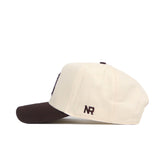 The No Rivals Arizona Espresso Hat is a cream-colored baseball cap with a dark brown brim. Made from high quality cotton, this structured hat has "NR" embroidered in brown on the side near the back.