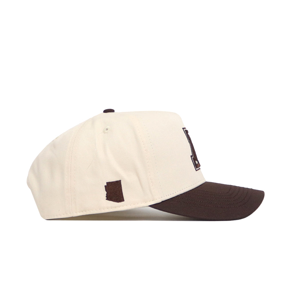The No Rivals Arizona Espresso Hat is a cream snapback with a dark brown brim, side patch, visible stitching, and structured fit, made from premium cotton and shown from the side.