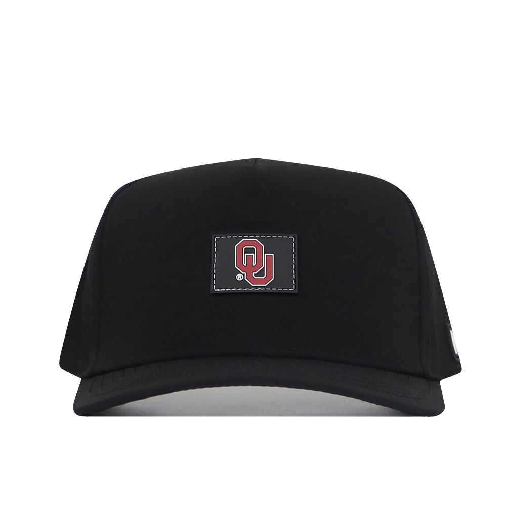 The Oklahoma Sooners Trainer Hat by No Rivals is a black snapback crafted from high-quality cotton with a structured fit, and features a rectangular patch on the front displaying the red OU logo for the University of Oklahoma.