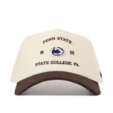 Introducing the Penn State Outlaw Hat - Classic by No Rivals: a beige baseball cap with a brown brim, featuring intricate embroidery of the Penn State logo and the words “Penn State 1855 State College, PA” on the front. Crafted for an ideal gameday fit, this hat includes a snap back closure for adjustable comfort.