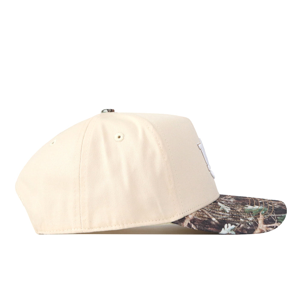 The No Rivals Auburn Camo Connector Hat is shown from the side on a white background, featuring a beige crown, a camouflage-patterned curved brim, and embroidered logos.