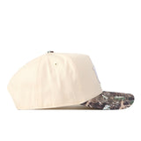 The No Rivals Auburn Camo Connector Hat is shown from the side on a white background, featuring a beige crown, a camouflage-patterned curved brim, and embroidered logos.