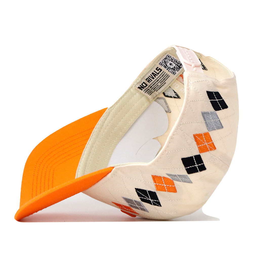 The Tennessee Argyle Hat by No Rivals is a beige baseball cap accented with an orange brim and an argyle pattern in black, orange, and gray. Crafted from a high-quality cotton blend, it is displayed upside down to showcase its inner tags, stitching details, and embroidered No Rivals logo. The snap back closure offers a comfortable and adjustable fit.