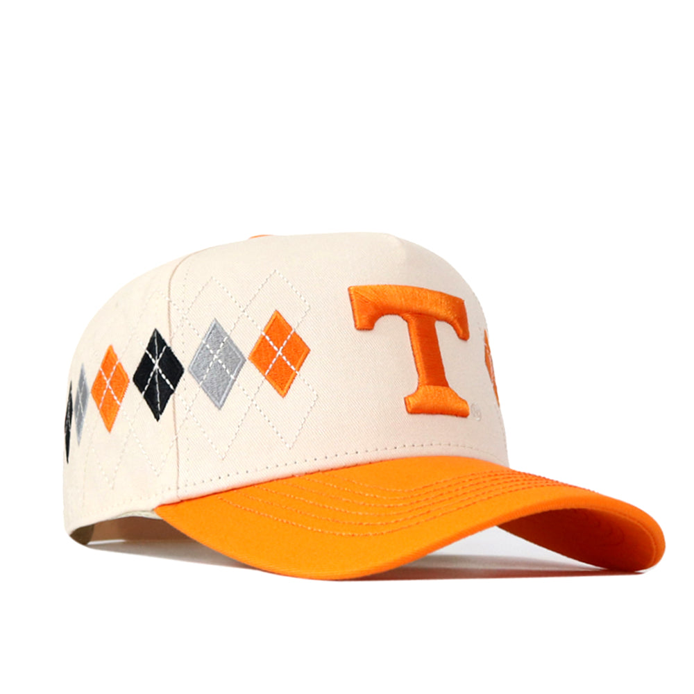 Introducing the Tennessee Argyle Hat by No Rivals—a stylish baseball cap crafted from a premium cotton blend. It features an eye-catching orange embroidered “T” on the front, an argyle pattern in orange, black, and gray on the side, and an orange brim. The adjustable snap back closure ensures a comfortable fit.