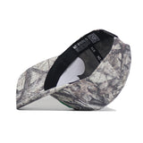 The No Rivals North Dakota Outland Hat is a structured, camouflage-patterned snapback baseball cap made from high-quality cotton. Shown side-on with brim down, it highlights the inside label and tags against a white background.