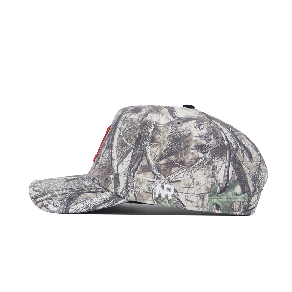 Side view of the Illinois Outland Hat by No Rivals in camouflage, featuring a small white logo on the side. Crafted from high-quality cotton, this snapback has a flat brim and structured crown for a comfortable fit.