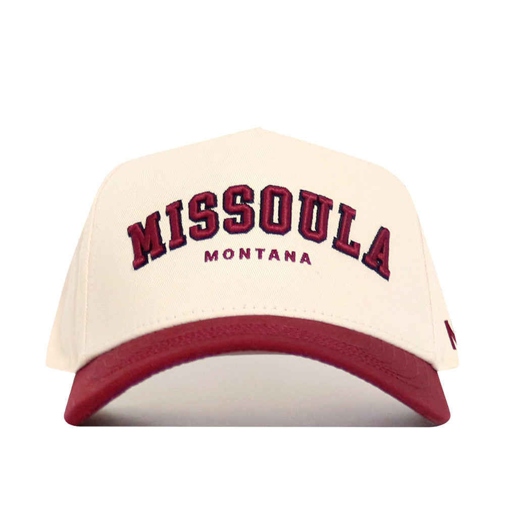 The Missoula Hometown Hat by No Rivals is a cream-colored, structured-fit cap with maroon "MISSOULA" and "MONTANA" lettering, a maroon brim, and high-quality cotton for comfort.