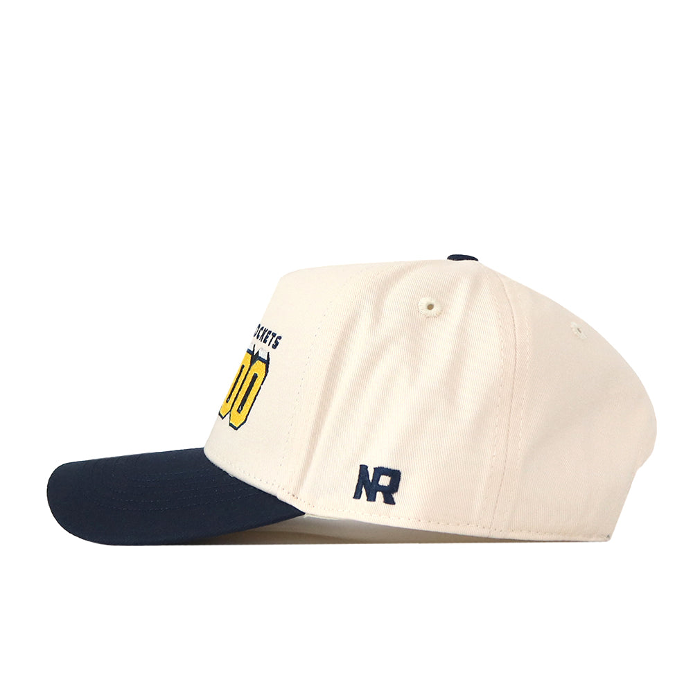 A cream-colored Toledo Alma Mater Hat by No Rivals with a navy blue brim, featuring the initials NR embroidered on the side and partially visible yellow and black text on the front. This officially licensed cap includes high-quality embroidered logos and a convenient snap-back adjustment for a comfortable fit.