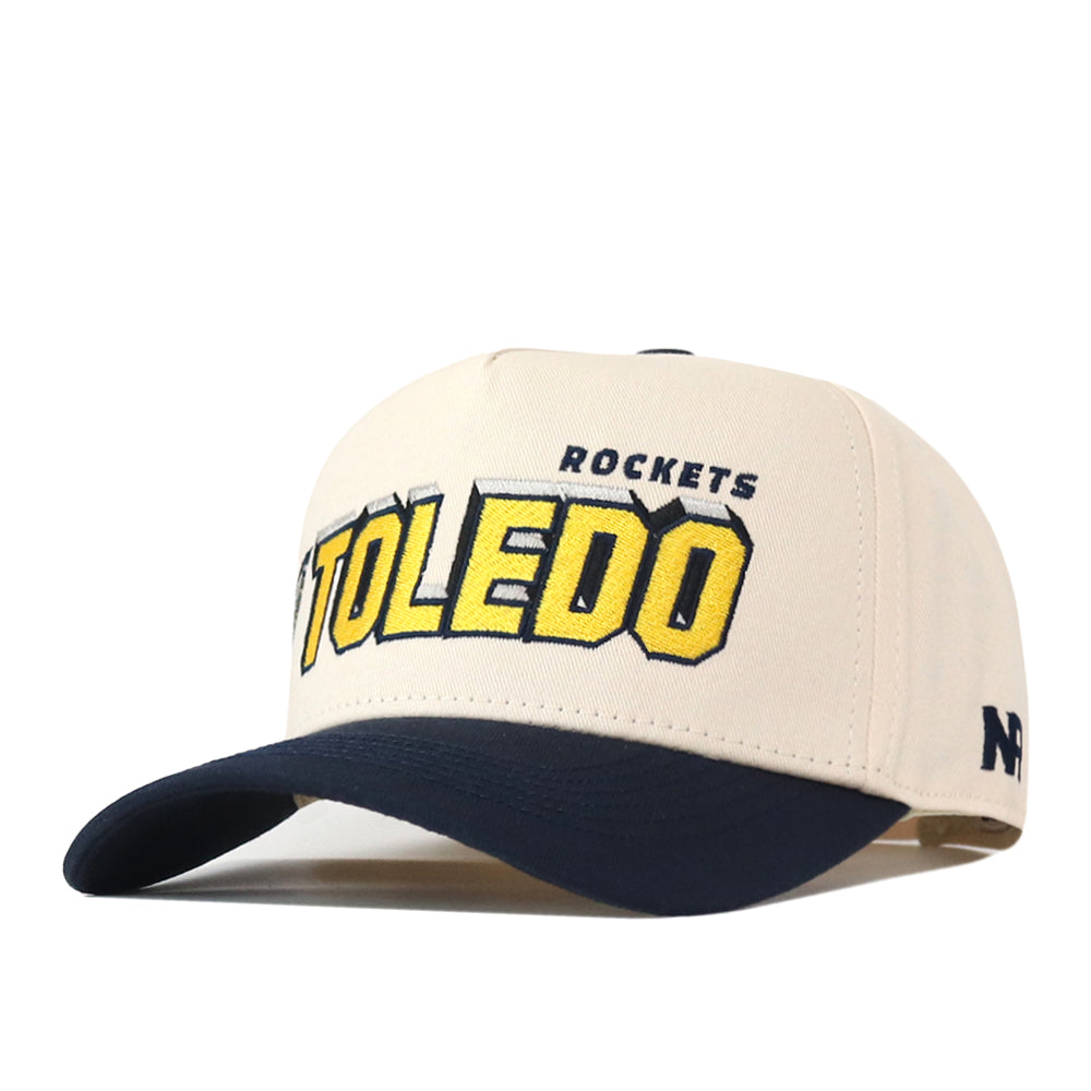 The No Rivals Toledo Alma Mater Hat is a beige and navy baseball cap featuring “TOLEDO ROCKETS” embroidered on the front in yellow and navy lettering. This officially licensed hat includes embroidered logos, a dark brim, a side logo, and an adjustable snap back for a comfortable fit.