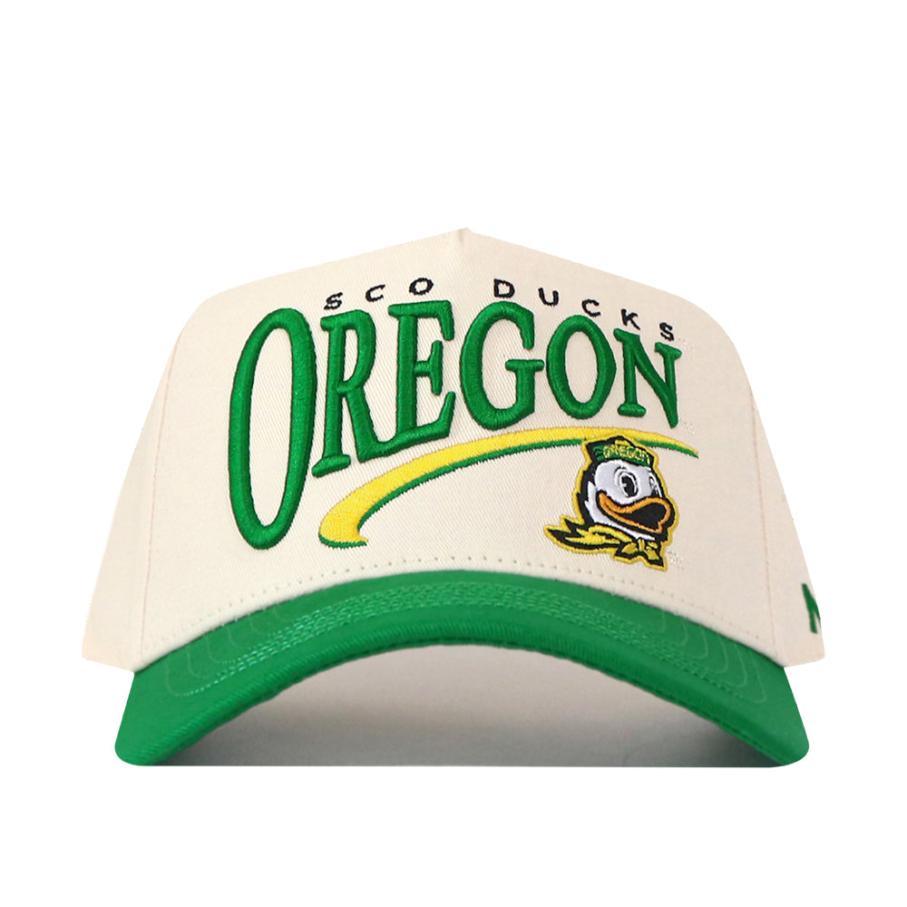 Introducing the Oregon Ducks Stride Hat by No Rivals—a structured fit baseball cap in white and green, featuring “OREGON,” the Oregon Ducks mascot, and “SCO DUCKS” above the lettering. Made from high-quality cotton, this snapback hat comes with a green brim and eye-catching yellow accents.