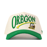 Introducing the Oregon Ducks Stride Hat by No Rivals—a structured fit baseball cap in white and green, featuring “OREGON,” the Oregon Ducks mascot, and “SCO DUCKS” above the lettering. Made from high-quality cotton, this snapback hat comes with a green brim and eye-catching yellow accents.