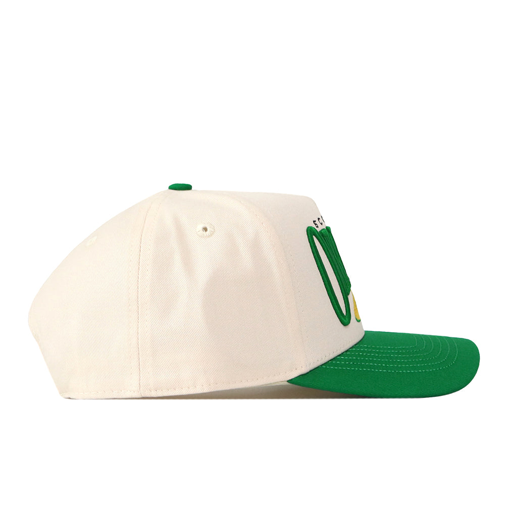 The Oregon Ducks Stride Hat by No Rivals is a white baseball cap with a green brim, viewed from the side. Made from high-quality cotton, this structured fit cap features green embroidered lettering and a small yellow accent on the front.