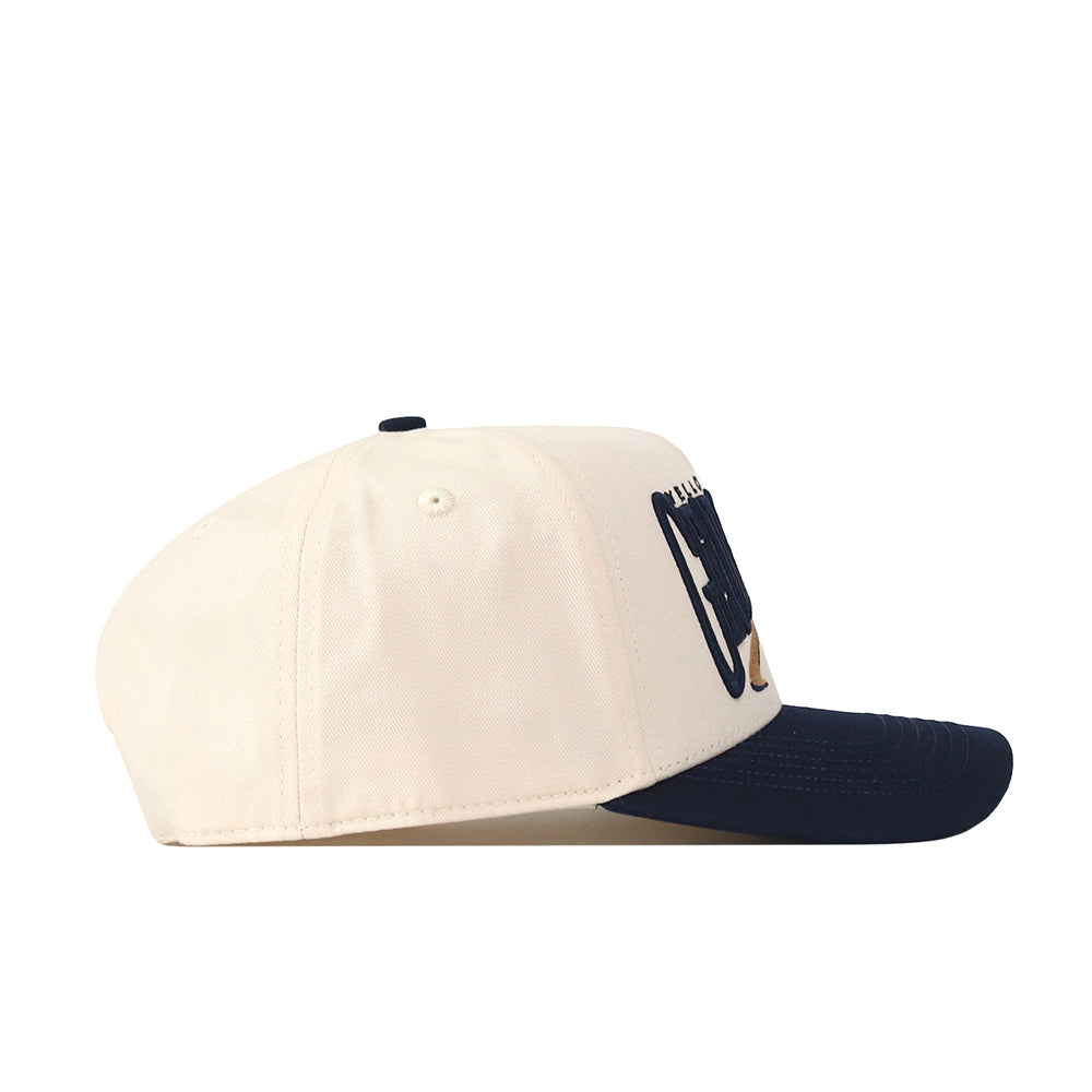 A side view of the No Rivals Georgia Tech STRIDE Hat showcases its cream-colored snapback design with a navy blue brim. Two eyelets are featured on the side, and a partial embroidered logo appears on the front—making it the perfect accessory to elevate your gameday fit.