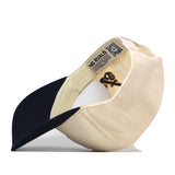 The Georgia Tech Yellow Jackets Halftime Hat by No Rivals is a beige and navy snapback baseball cap. When turned inside out, the hat reveals detailed stitching, a “NO RIVALS” label, and a QR code on the inner band. The navy bill complements an officially licensed embroidered Georgia Tech logo on the front, combining standout craftsmanship with unique design.