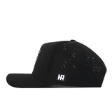 A side view of the Florida Gators Football Mascot Hat in black by No Rivals, featuring small perforated holes for ventilation and a rectangular patch with “NR” in white letters on the lower side. Made from high-quality performance fabric, this hat delivers comfort and durability for everyday wear.