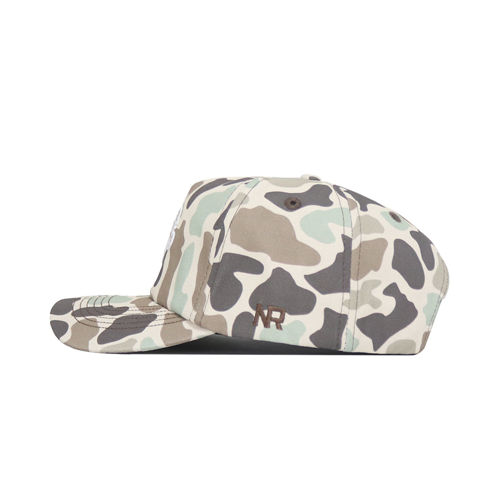 A side view of the NDSU Huntsman Hat by No Rivals—a green, beige, and brown duck camo 5-panel cap with "NR" embroidered in dark thread on the side.