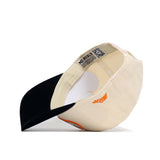 The Tennessee Baseball Slugger Hat by No Rivals is shown upside down, displaying its cream color, black bill, inside label reading “NO RIVALS,” and an orange winged logo embroidered on the side.
