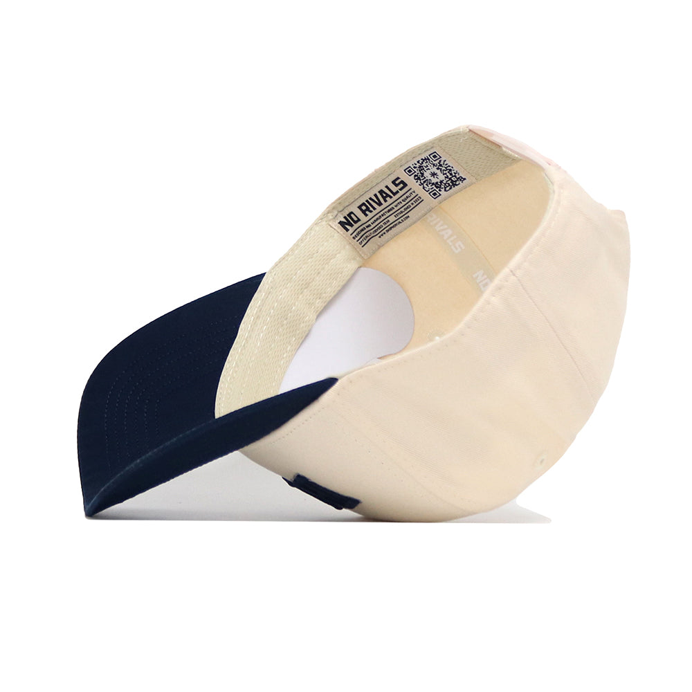 The Reno Hometown Hat by No Rivals is shown from below, featuring a cream cotton crown, navy blue brim, structured fit, white sweatband, and a NO RIVALS label inside the crown.