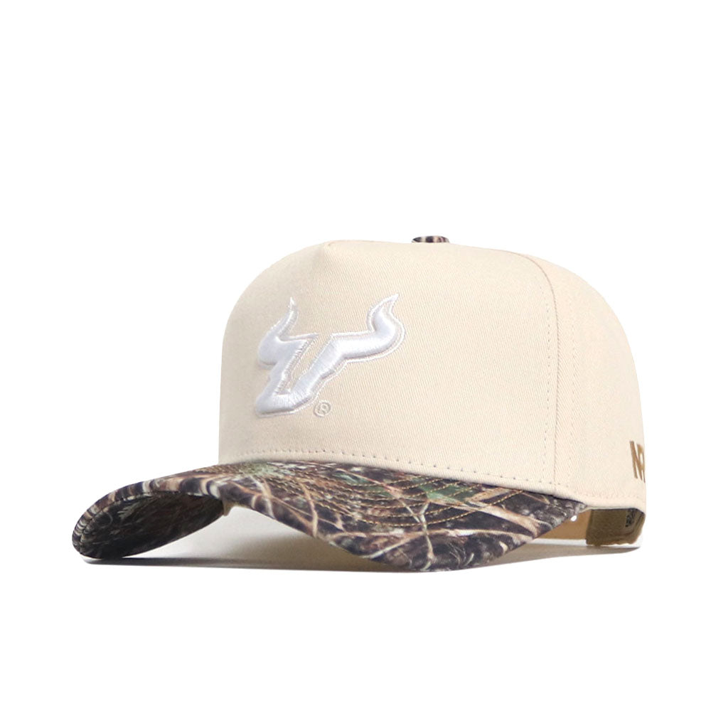 The No Rivals USF Camo Connector Hat features a beige snapback design, white embroidered bull logo, curved camo brim, and structured fit crafted from high-quality cotton.