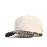 The No Rivals USF Camo Connector Hat features a beige snapback design, white embroidered bull logo, curved camo brim, and structured fit crafted from high-quality cotton.