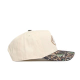 The No Rivals Florida Camo Connector Hat is a beige baseball cap with a camo-patterned pre-curved brim, side view, featuring an embroidered front logo and a snapback closure for a comfortable, structured fit.