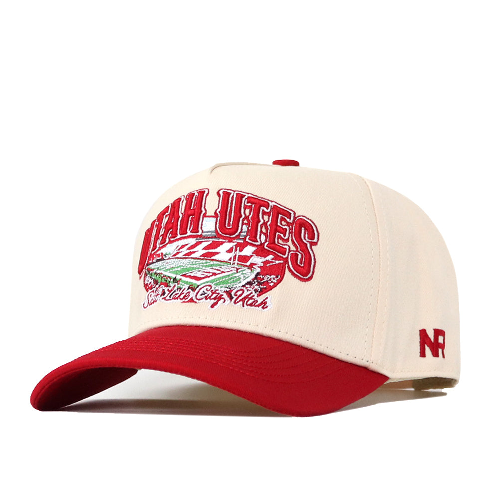 Show your Utah Utes pride with the officially licensed Utah Utes Stadium Hat by No Rivals, a beige and red snapback featuring bold embroidered Utah Utes and stadium graphics on the front, “Salt Lake City, Utah” stitched below, and striking red NR initials on the side.
