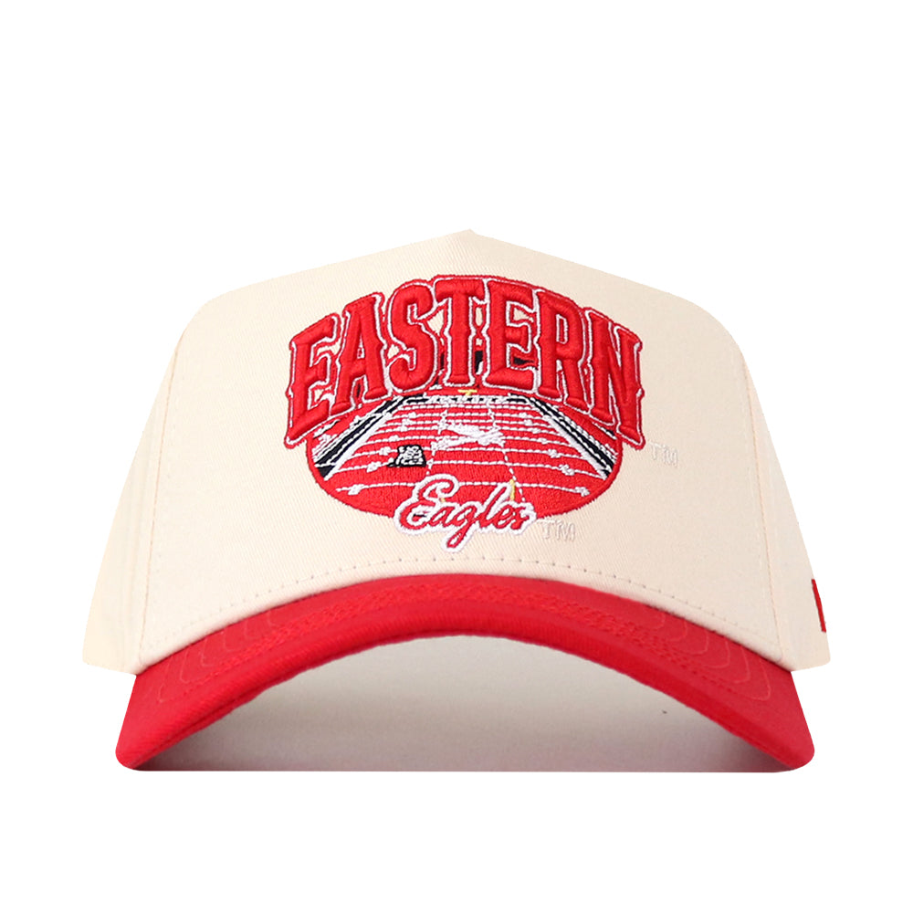 Introducing the No Rivals EWU Eagles Stadium Hat, featuring a beige performance fabric crown and a solid red brim. The hat showcases an embroidered Eastern Eagles logo in red and white above a running track graphic, all in a stylish snapback design.